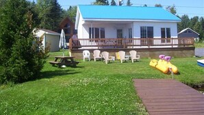 A house with a blue roof, a fenced deck, and outdoor seating.