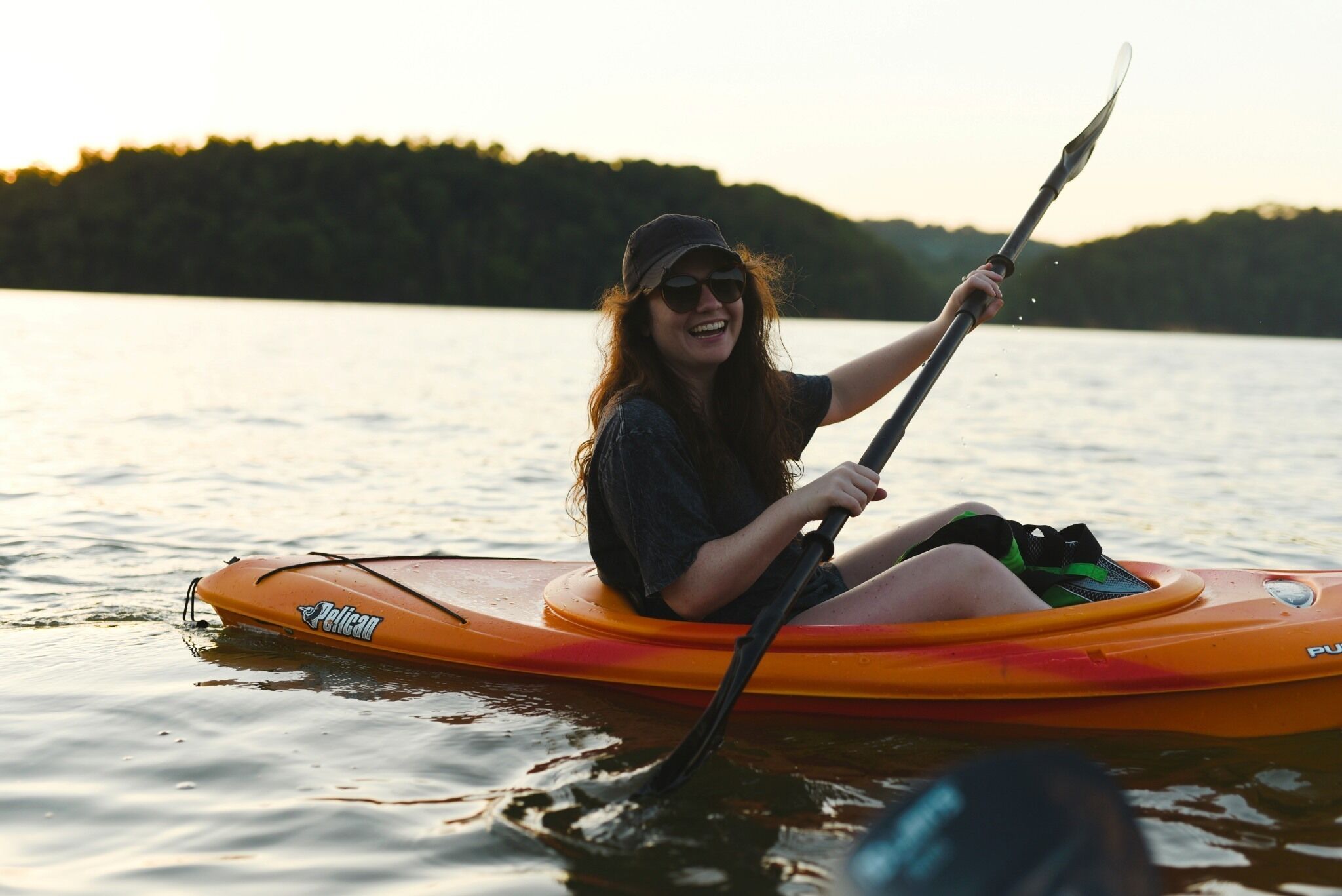 A person sitting on a kayak with a paddle, on a body of water.