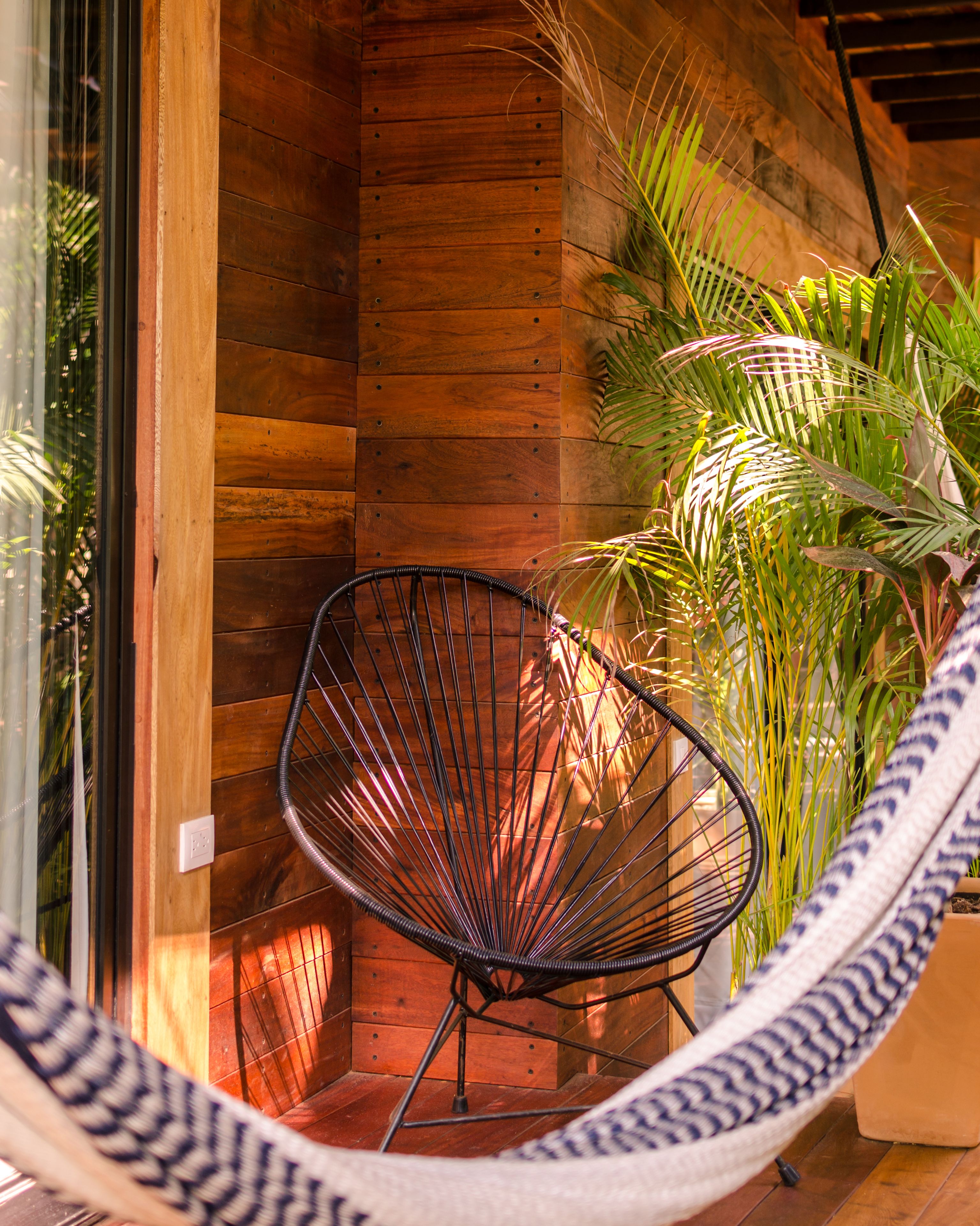 Una silla hamaca en una habitación de madera con vistas al exterior.
