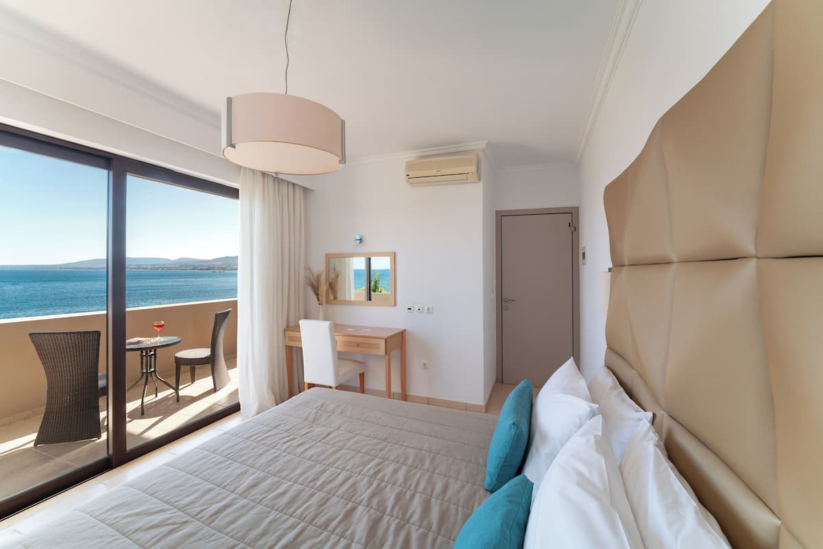 Habitación de hotel con cama, escritorio, silla y vista al mar.