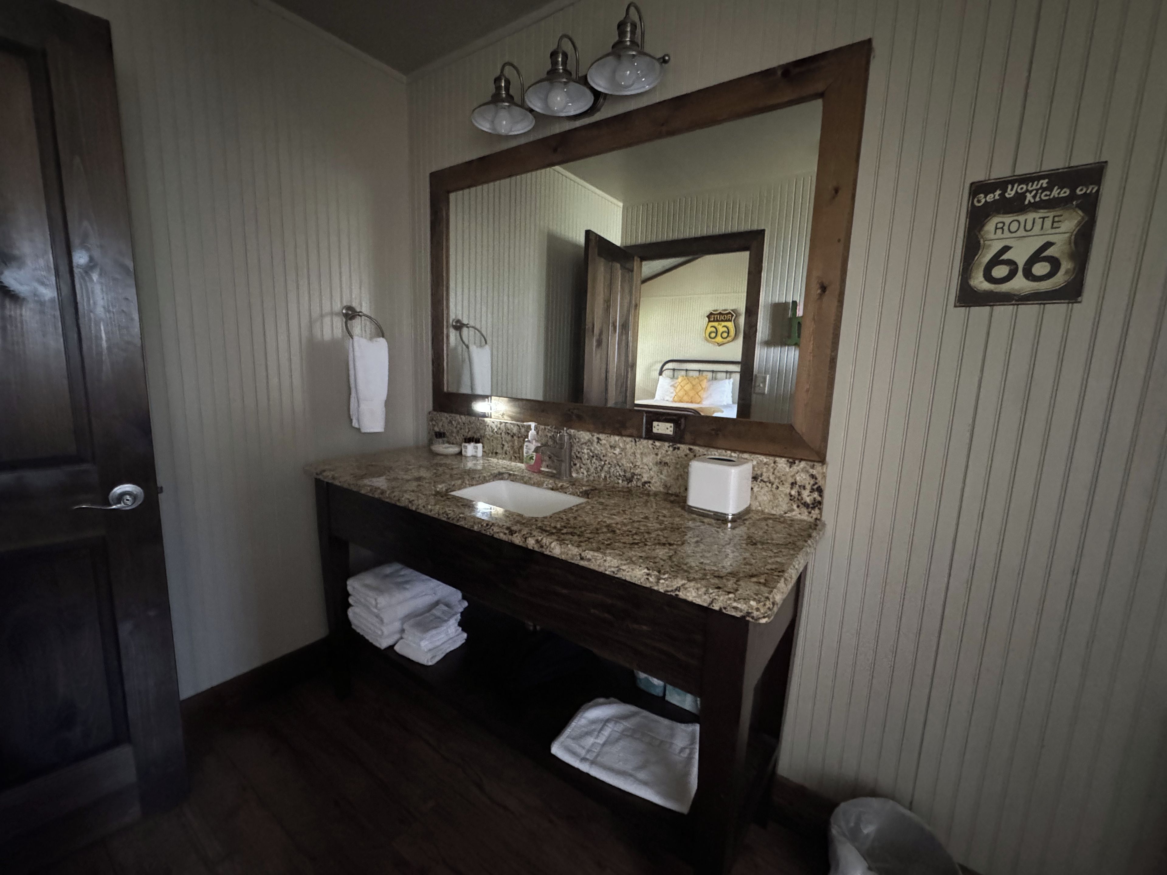 A bathroom with a wooden vanity, a sink, a mirror, and a towel rack.