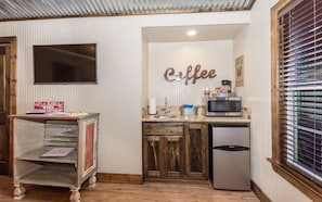 Una cocina compacta con refrigerador, microondas y un cartel que dice 'café' en la pared.