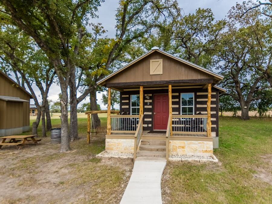 A rustic cabin with a porch, a red door, and a number '9' sign.