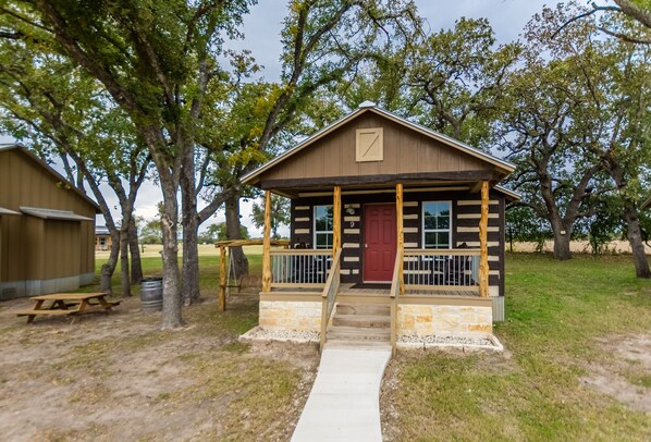 A rustic cabin with a porch, a red door, and a number '9' sign. - Vineyard Trail Cottages - Adults Only (Fredericksburg)