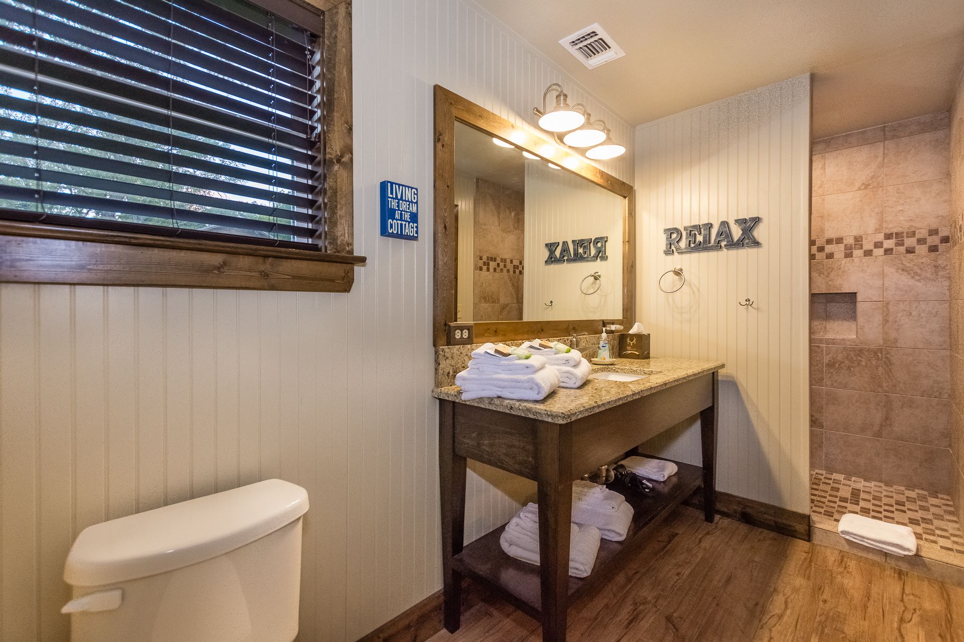 Une salle de bain avec un meuble-lavabo en bois, des toilettes et un espace douche.