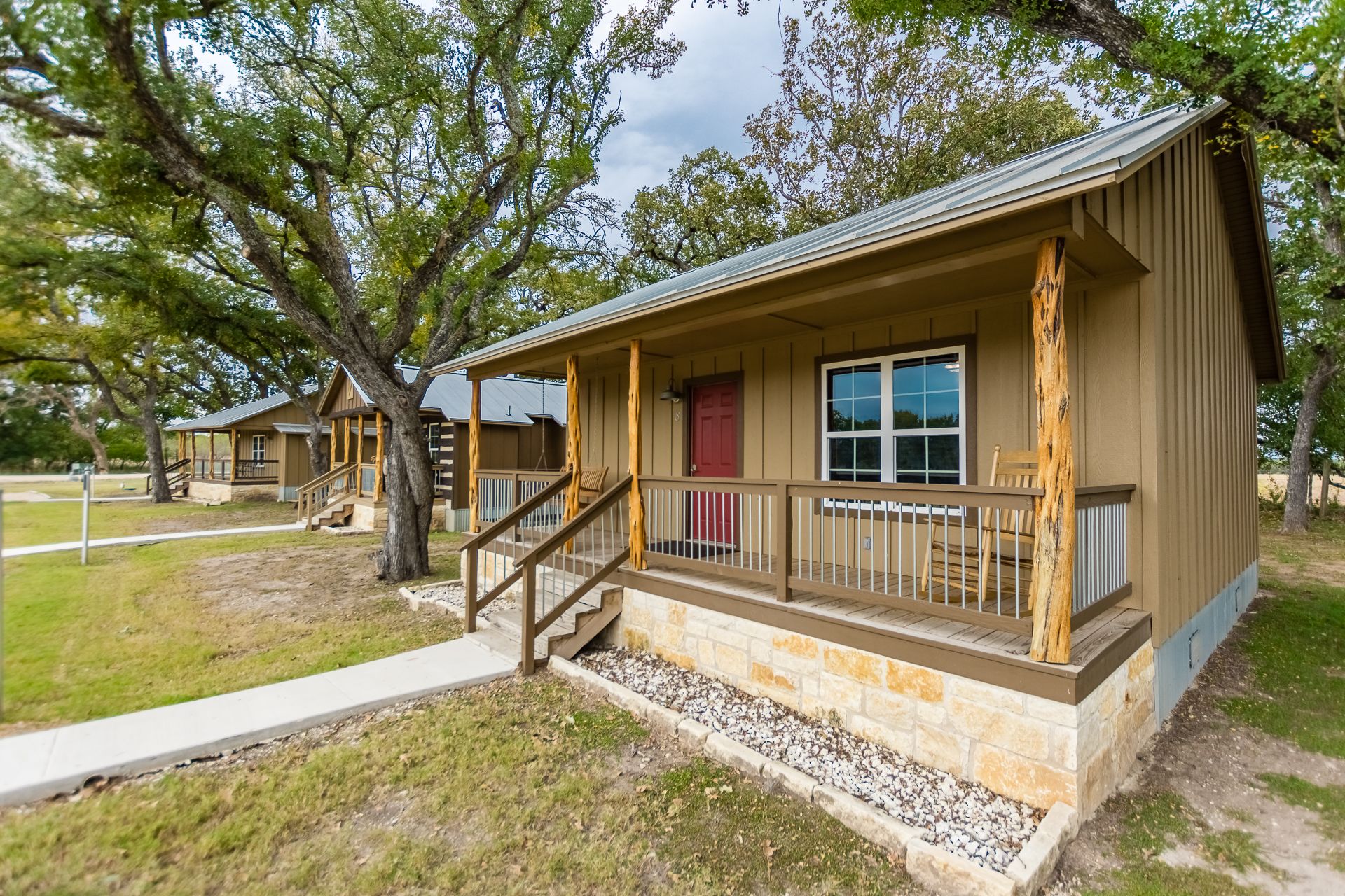 A lodge with a porch, stone foundation, and a red door.