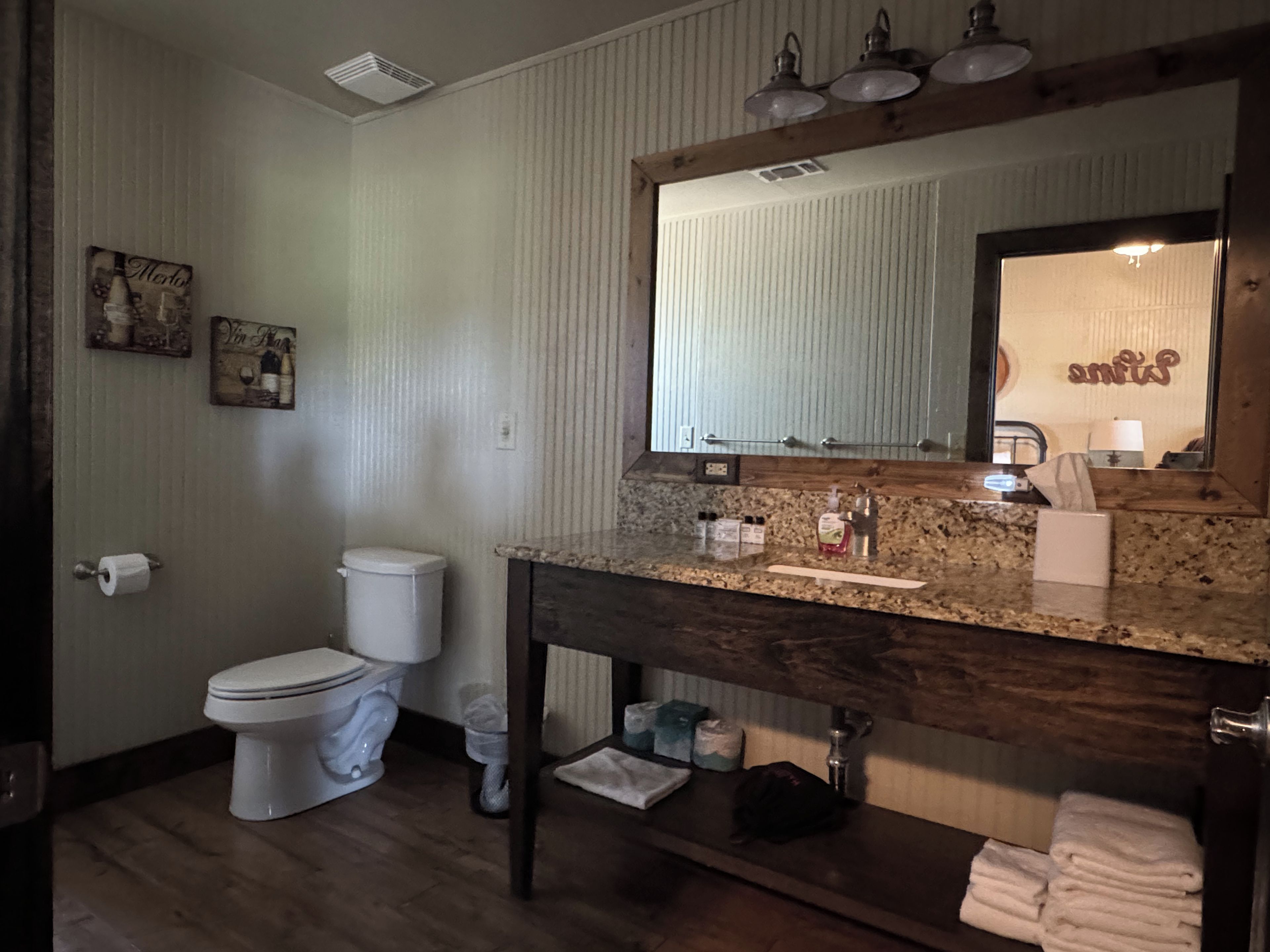 Un baño con inodoro, lavamanos, espejo y toallero.