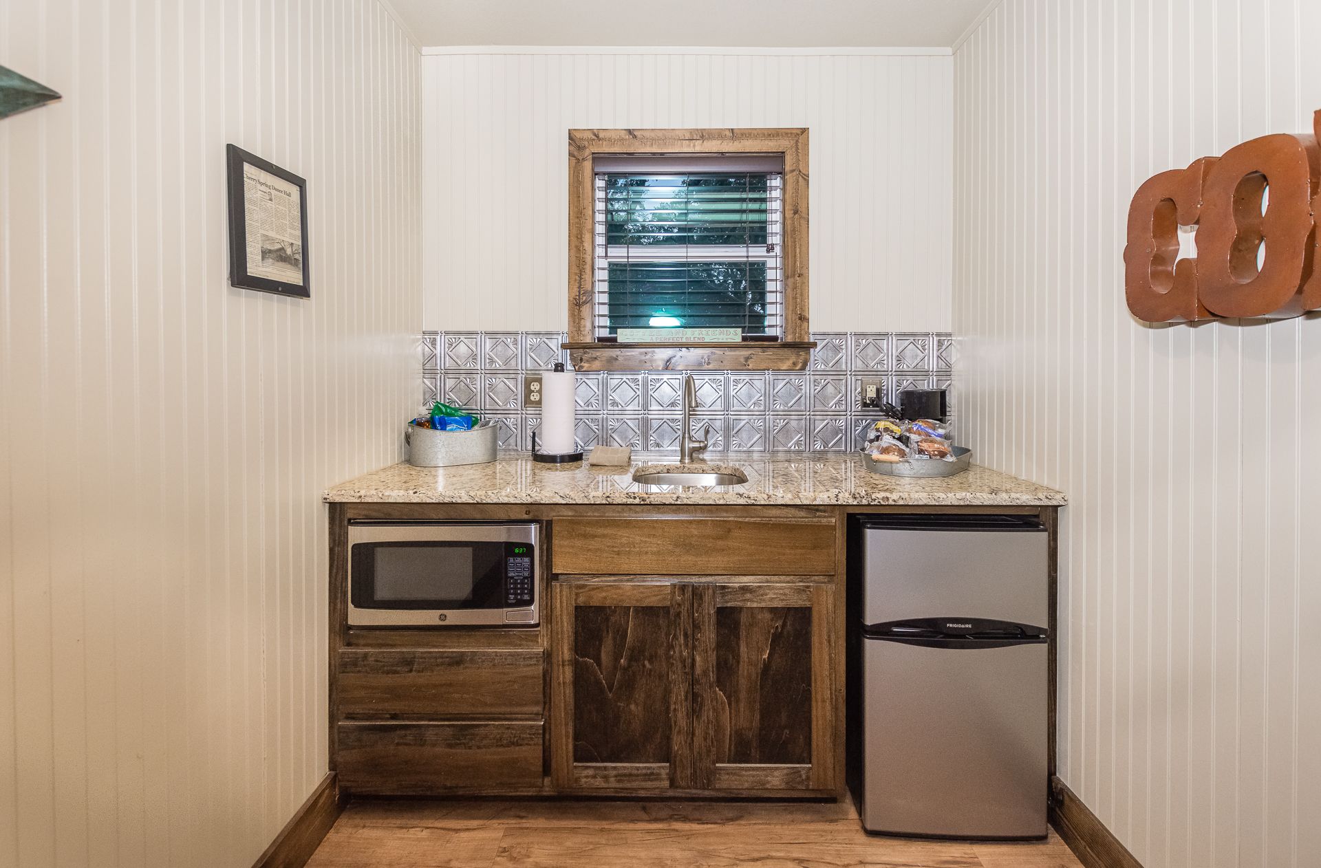 Cocina compacta con microondas, refrigerador y armarios de madera.
