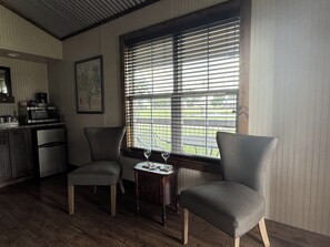 Une pièce comprenant deux fauteuils rembourrés, une petite table avec un verre à vin, un four à micro-ondes et un réfrigérateur.