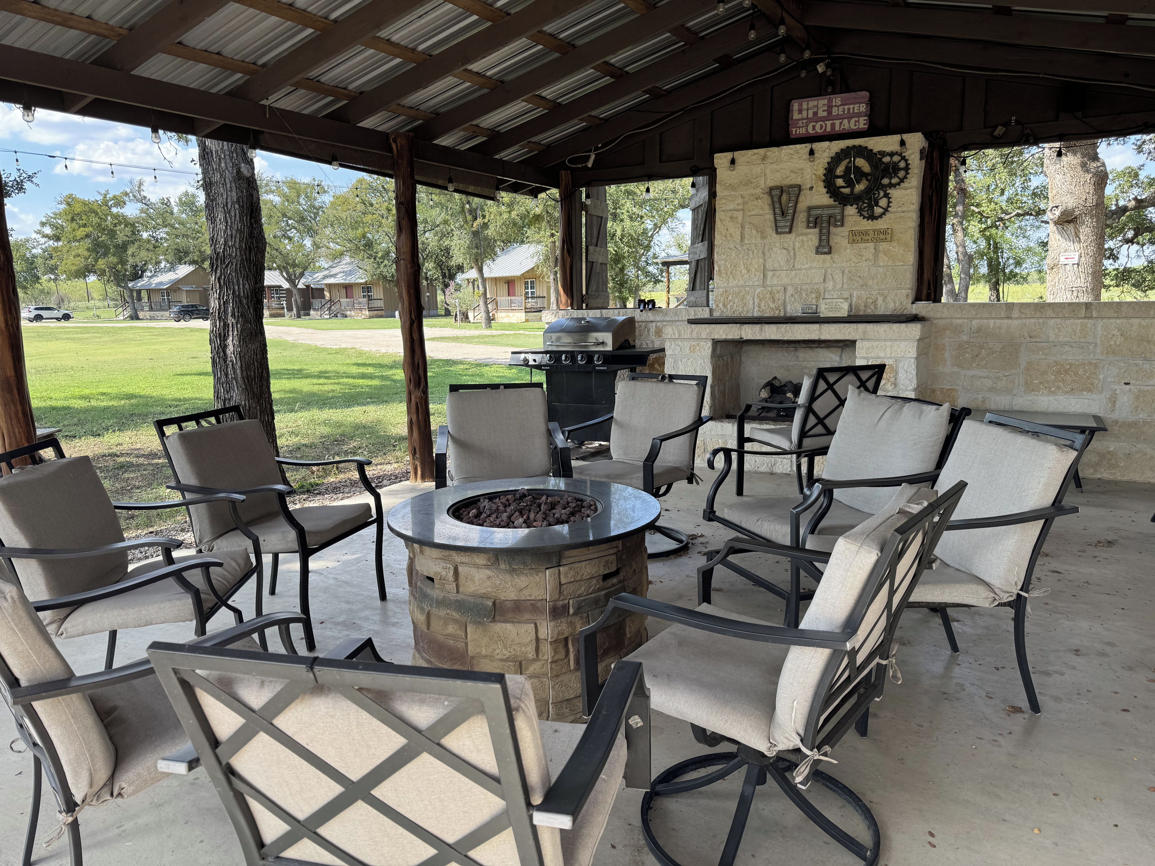 An outdoor patio with a stone fire pit, seating, and a grill.