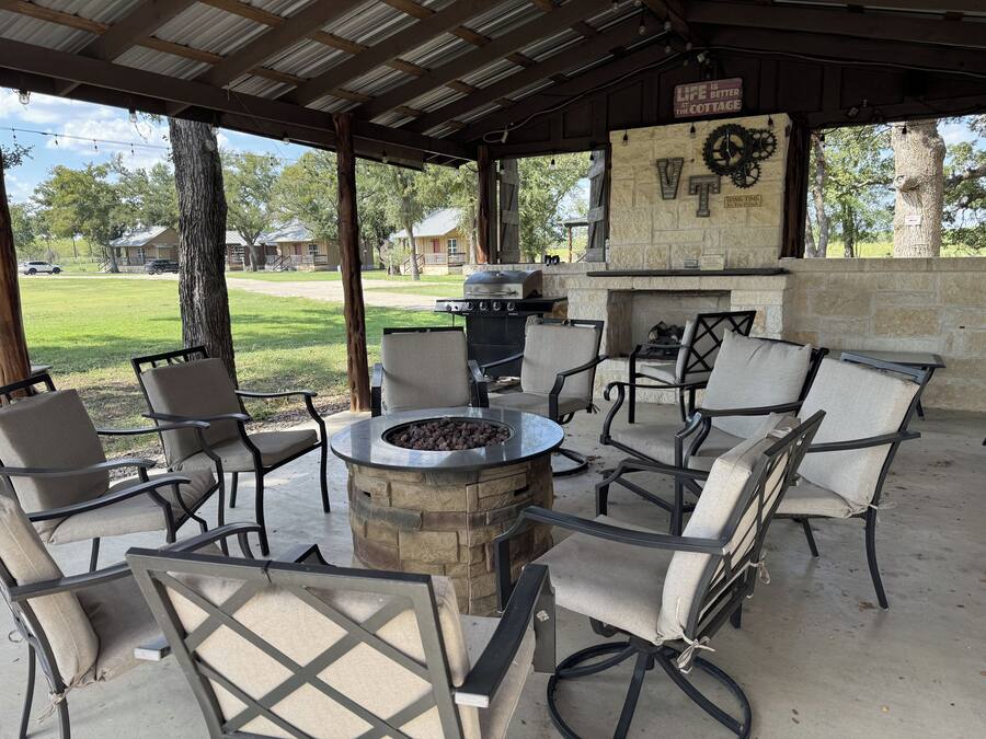 An outdoor patio with a stone fire pit, seating, and a grill.