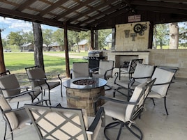 An outdoor patio with a stone fire pit, seating, and a grill.
