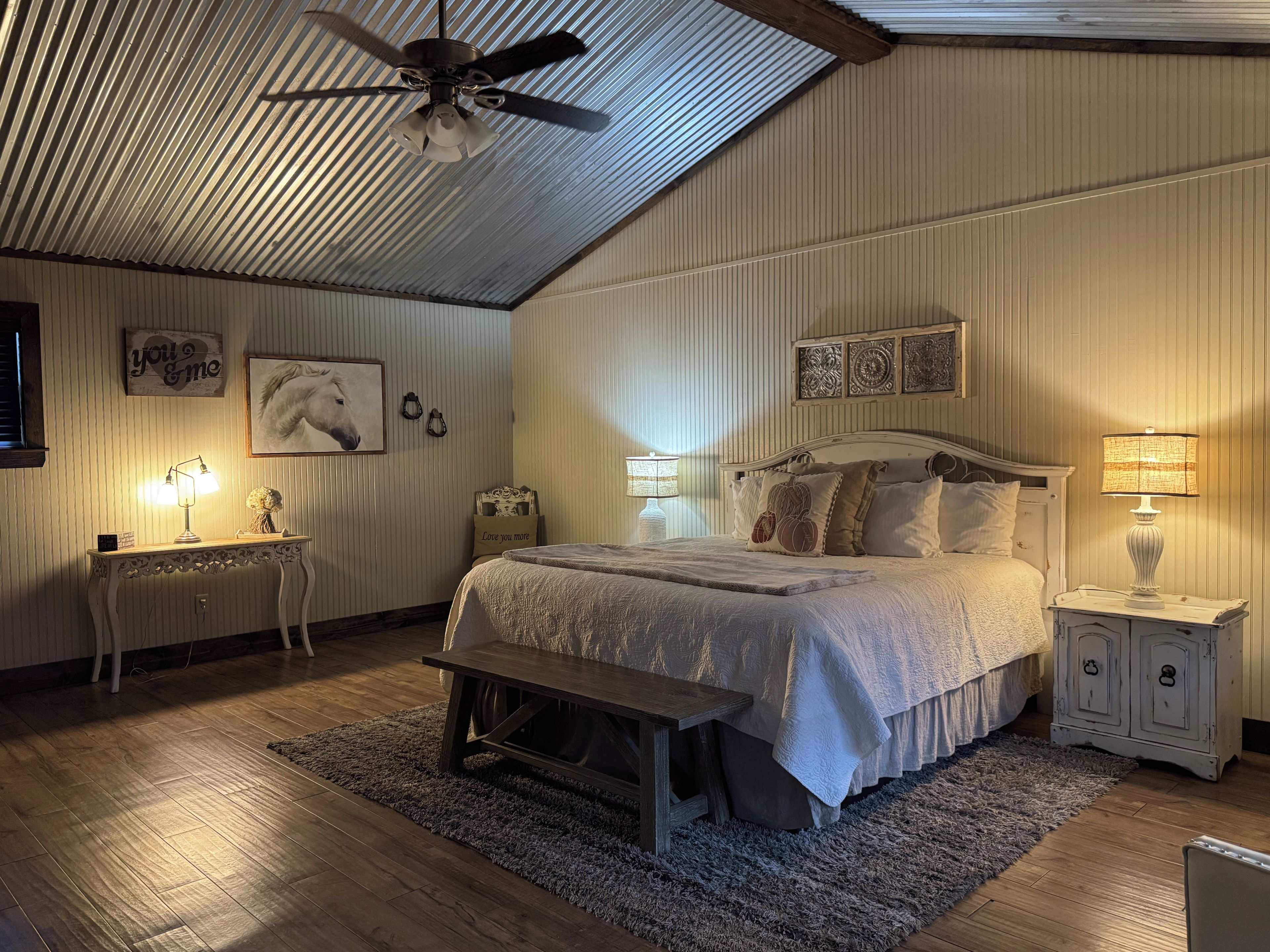 A bedroom with a bed, bedside tables, a ceiling fan, and wall-mounted decor.