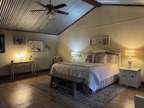 A bedroom with a bed, bedside tables, a ceiling fan, and wall-mounted decor. - Vineyard Trail Cottages - Adults Only (Fredericksburg)