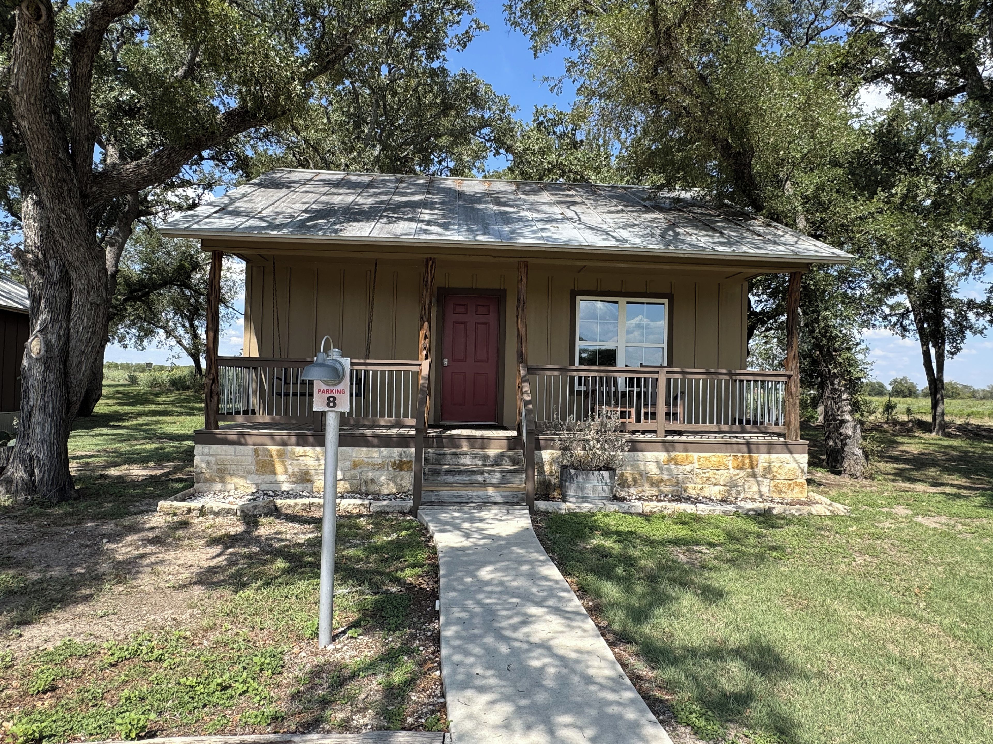 A single-story house with a porch, a red door, and a parking sign indicating 8 spaces.