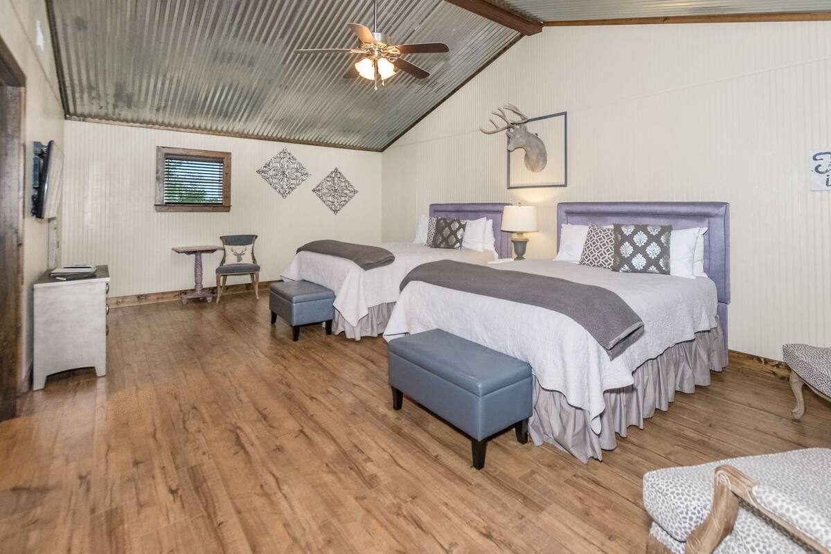 Una habitación con dos camas, un ventilador de techo, una decoración con cabeza de venado y un letrero que dice 'This is the'.