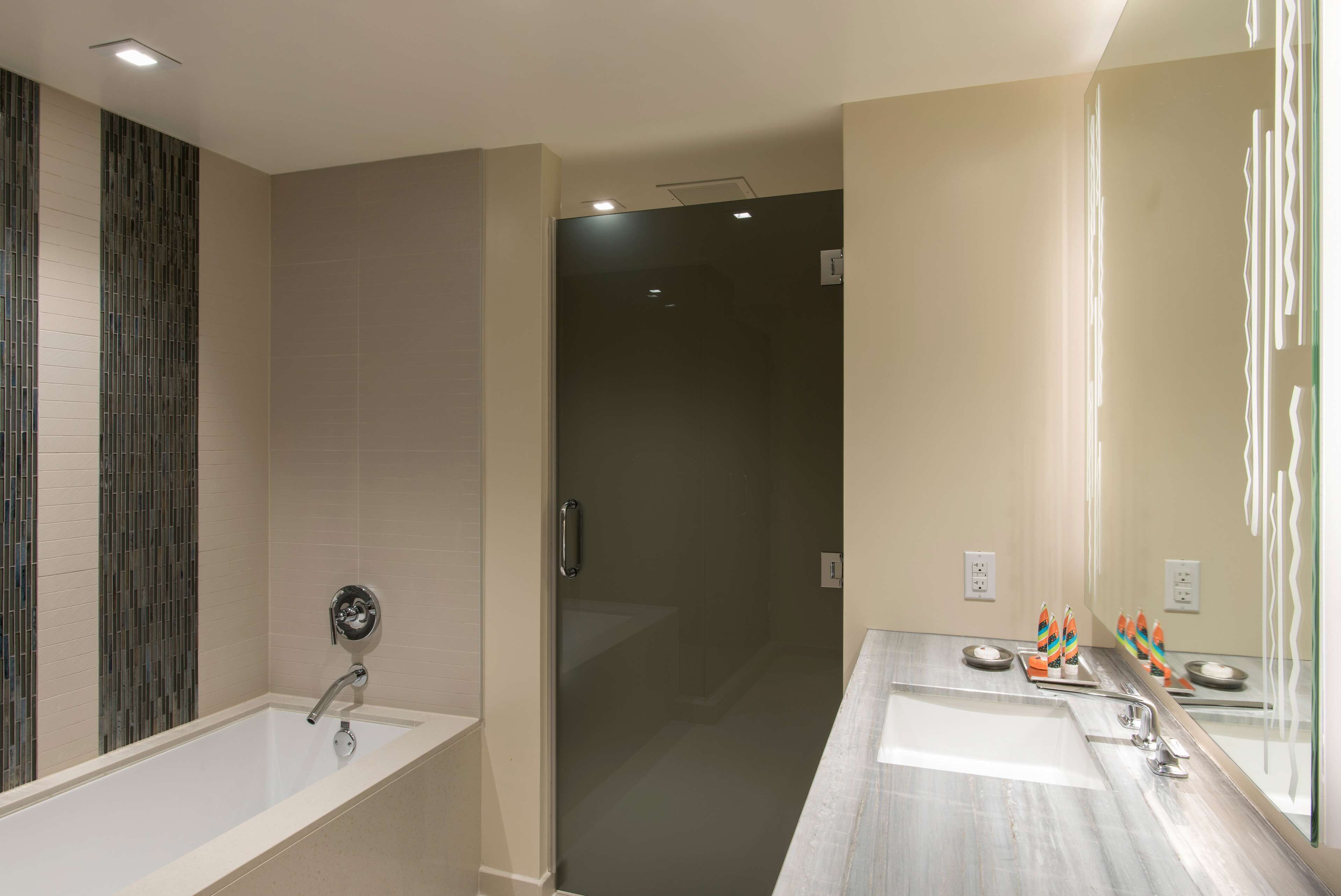 A modern bathroom with a glass shower enclosure, a large bathtub, and a vanity with two sinks.
