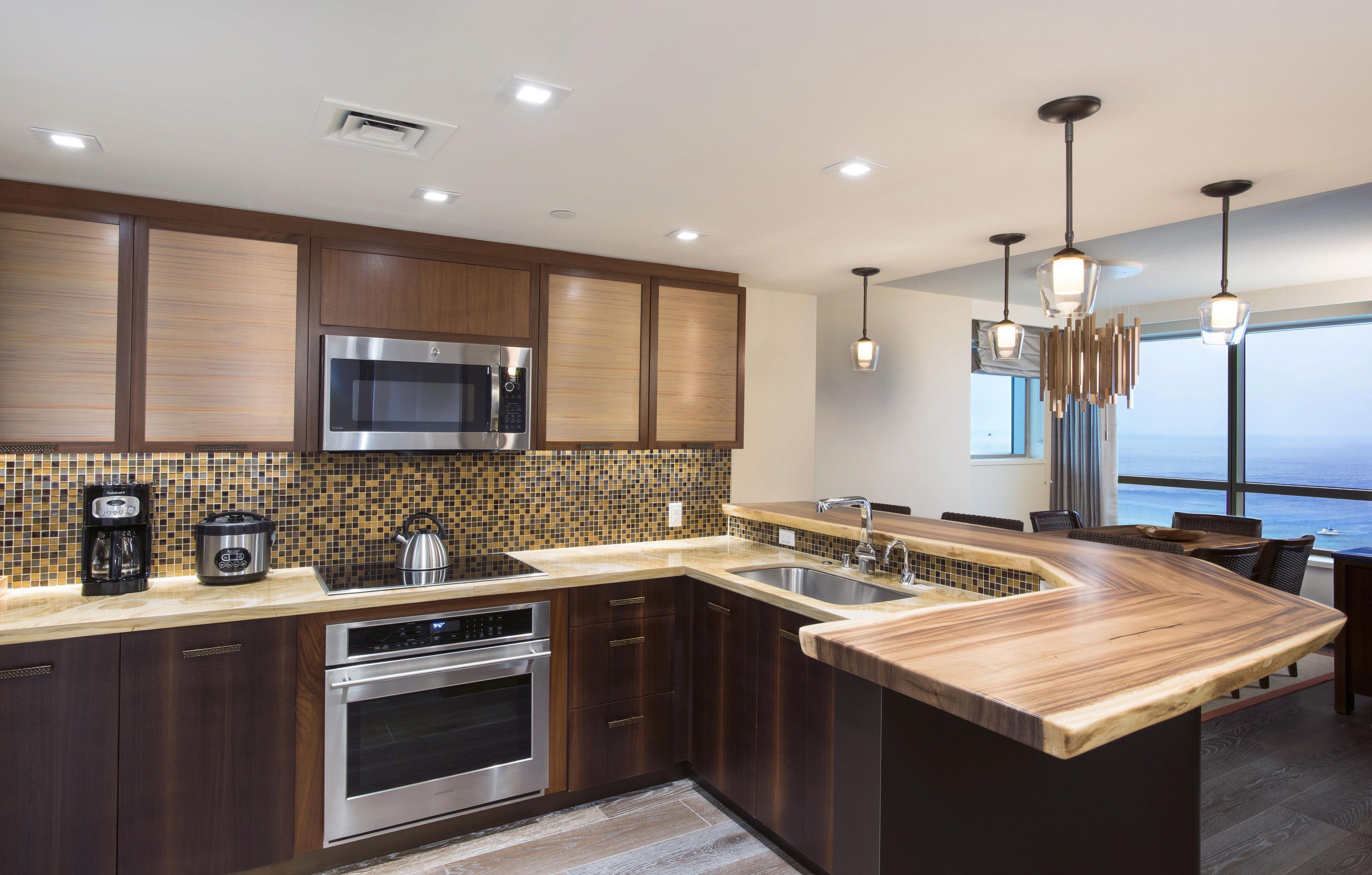 A modern kitchen with a large island, stainless steel appliances, and a view of the ocean.