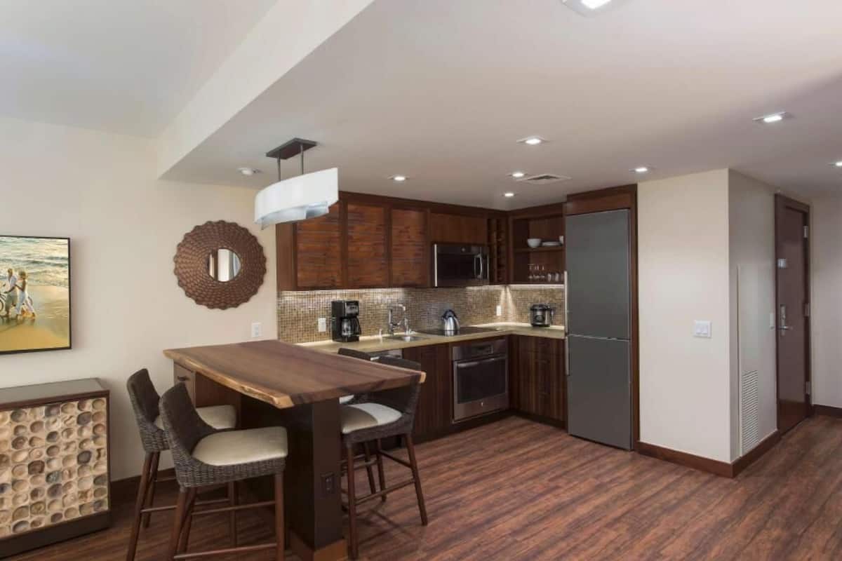Eine moderne Küche mit dunklen Holzschränken, einem Edelstahlkühlschrank und einer Essecke mit Holztisch und Korbstühlen.