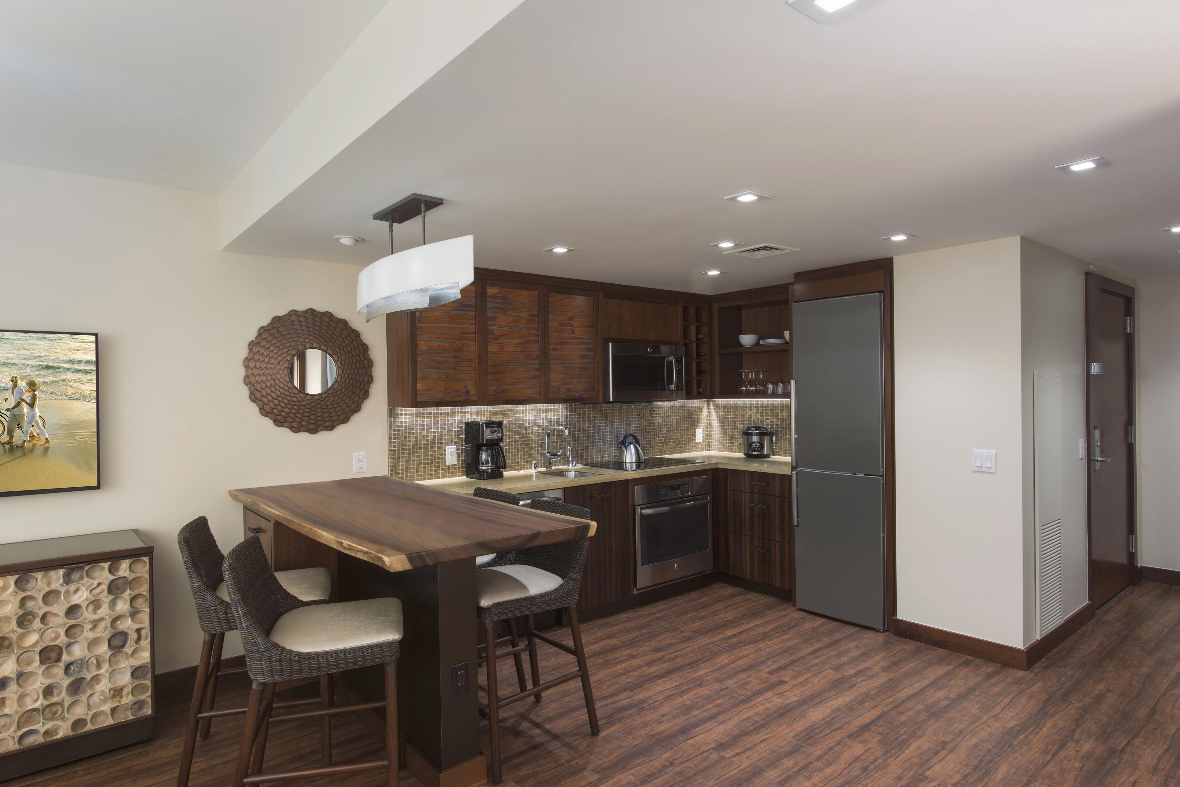 A compact kitchen with a dining area, equipped with a refrigerator, oven, microwave, and coffee maker.