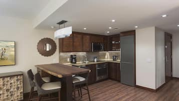 A compact kitchen with a dining area, equipped with a refrigerator, oven, microwave, and coffee maker.