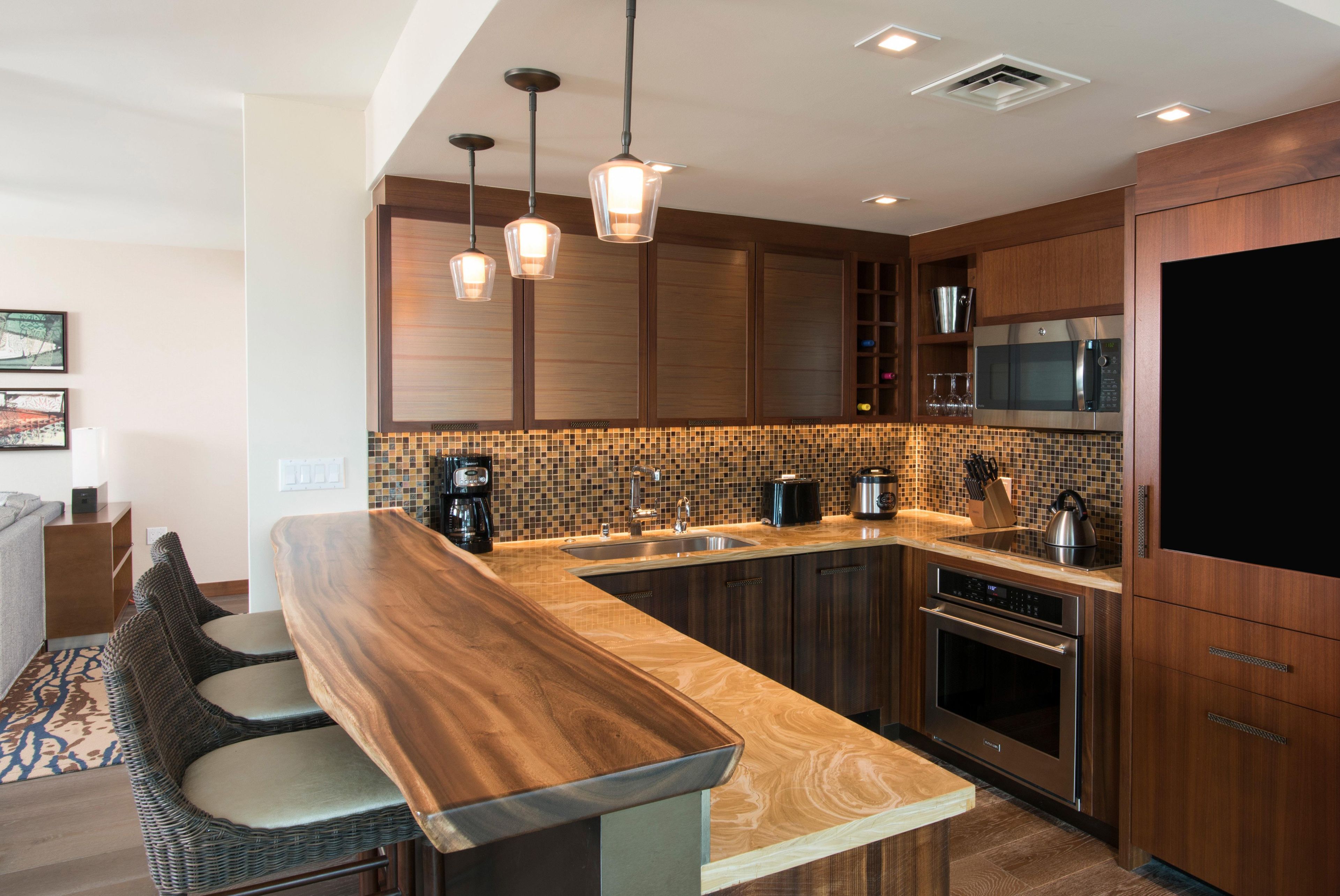 Una cocina moderna con una isla de madera, electrodomésticos de acero inoxidable e iluminación colgante.