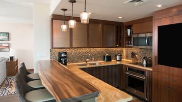 Una cocina moderna con una isla de madera, electrodomésticos de acero inoxidable e iluminación colgante.