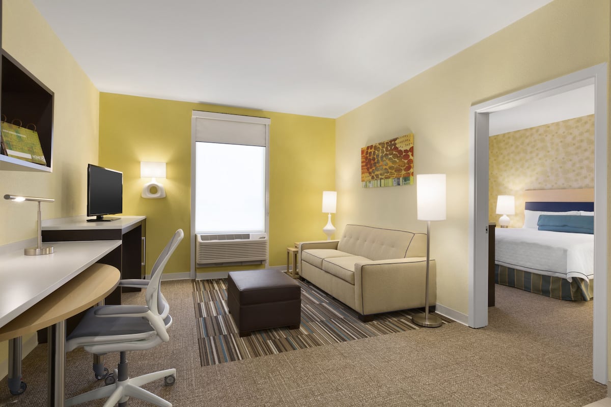 A hotel room with a desk, chair, sofa, and a bed.