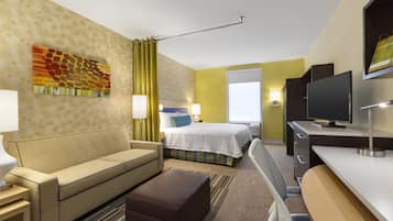 A hotel room with a bed, a sofa, a desk, and a television.