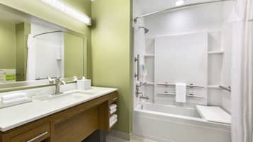 A modern bathroom with a double sink vanity, a large mirror, a shower with a glass door, and a bathtub.