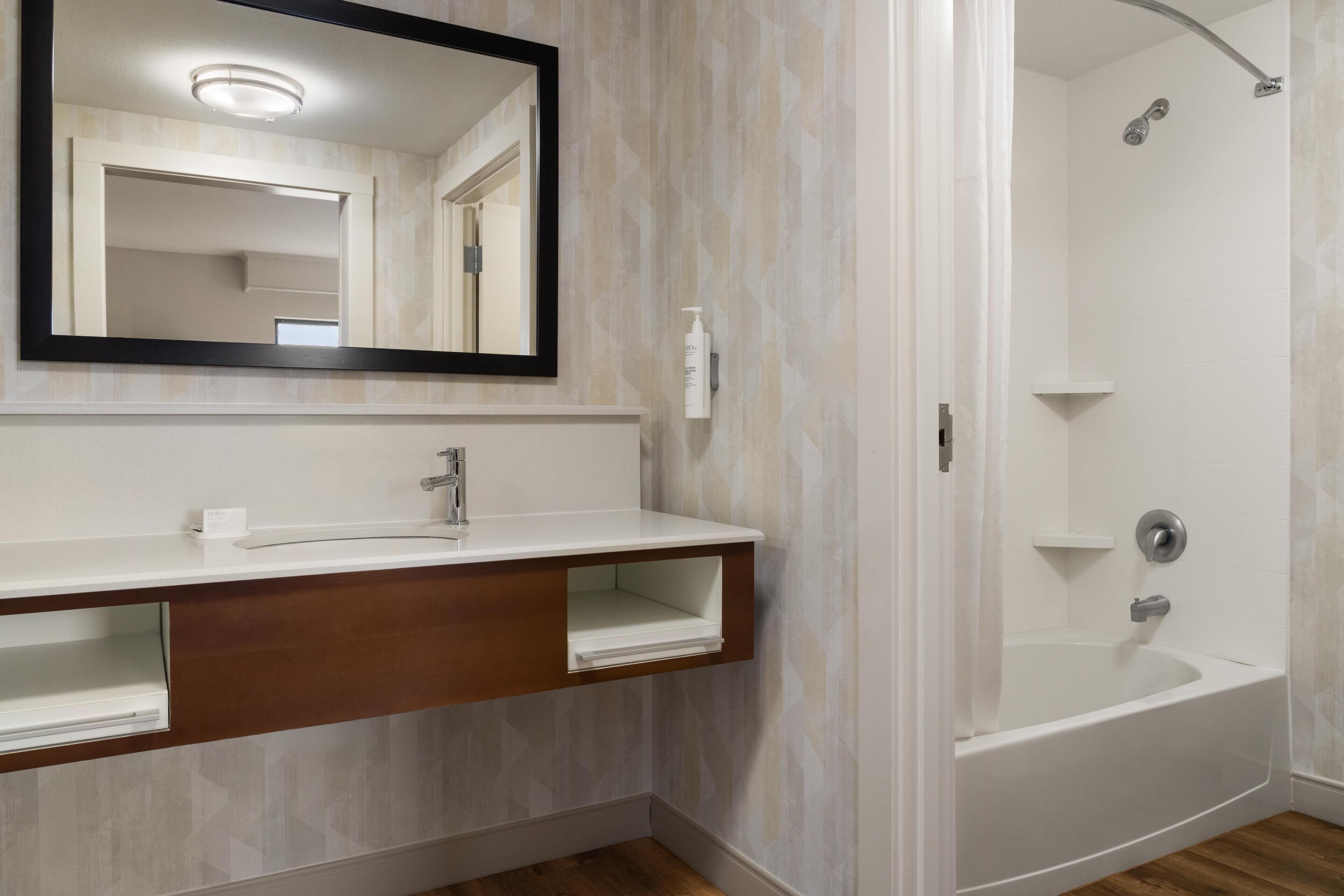 Une salle de bain avec un lavabo blanc, un miroir et une douche.