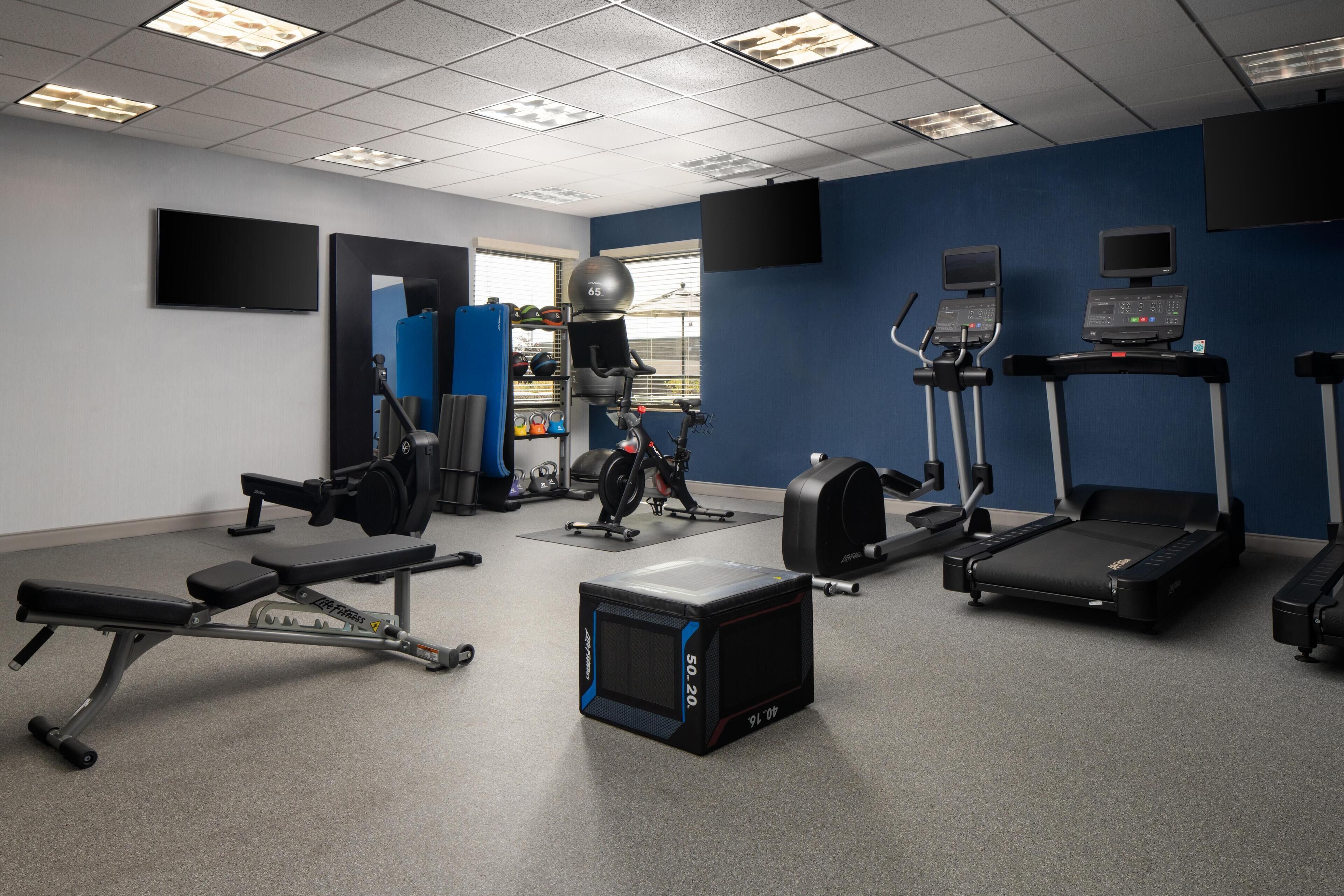 Una palestra con diverse attrezzature per l'allenamento, tra cui tapis roulant, cyclette e macchinari per pesi.