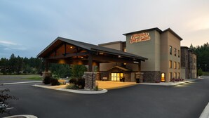 Un hotel Hampton Inn & Suites con entrada cubierta, fachada de piedra y un letrero acogedor.