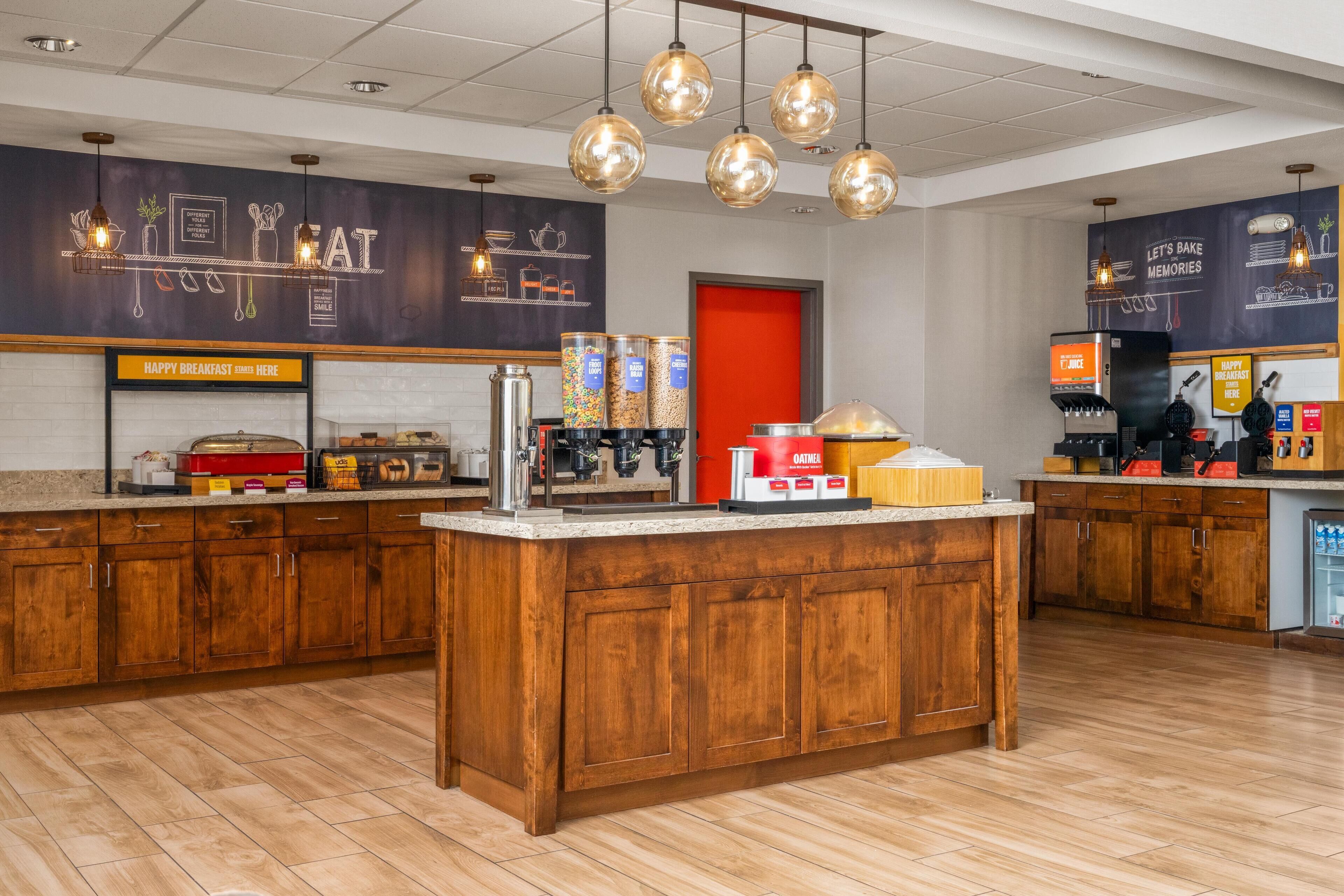 A modern kitchen area with wooden cabinets, a central island, and various coffee-making equipment.