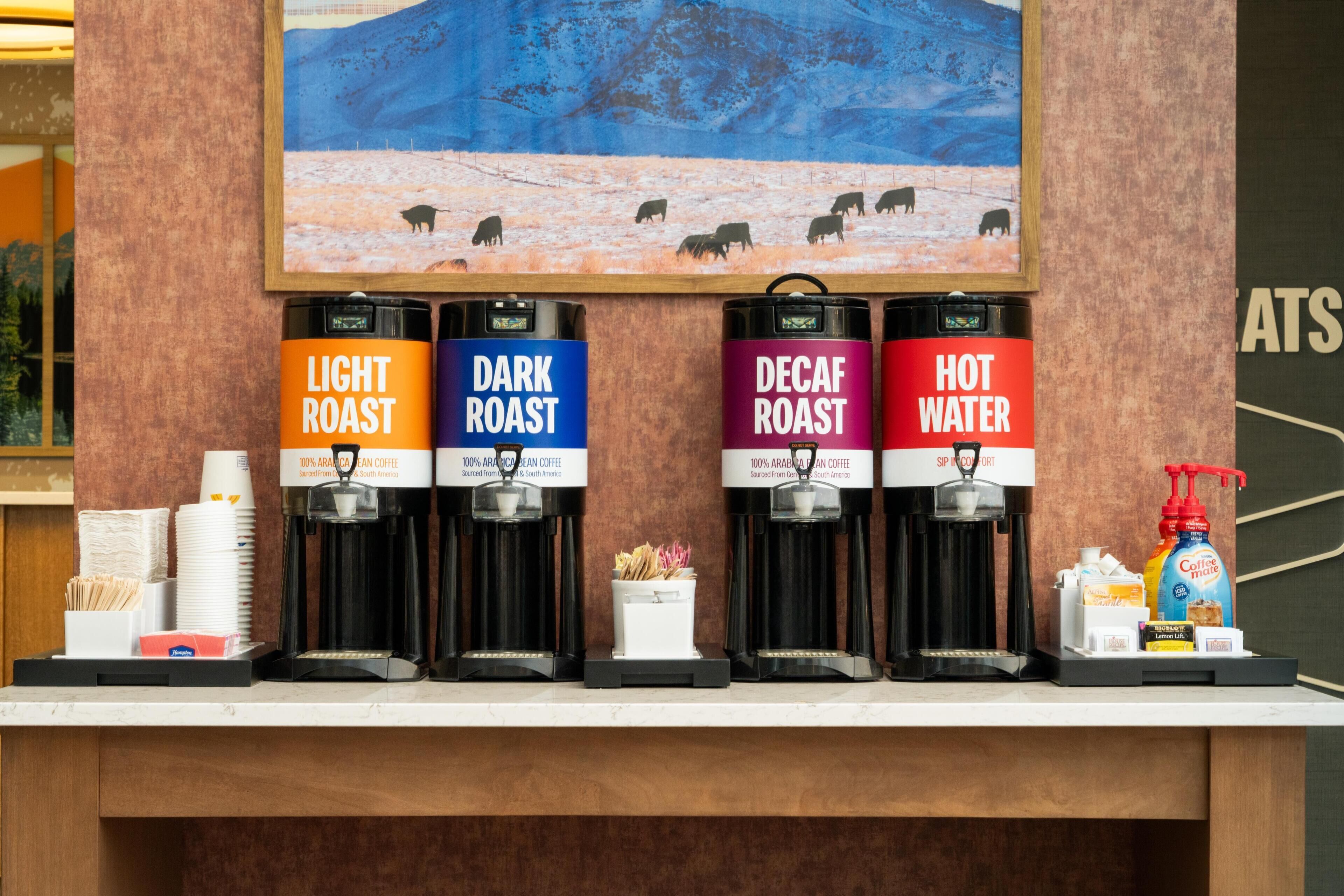 A coffee station with four dispensers labeled 'Light Roast,' 'Dark Roast,' 'Decaf Roast,' and 'Hot Water.'
