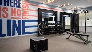Un gimnàs amb equipament de musculació, una pica i un mur motivacional.