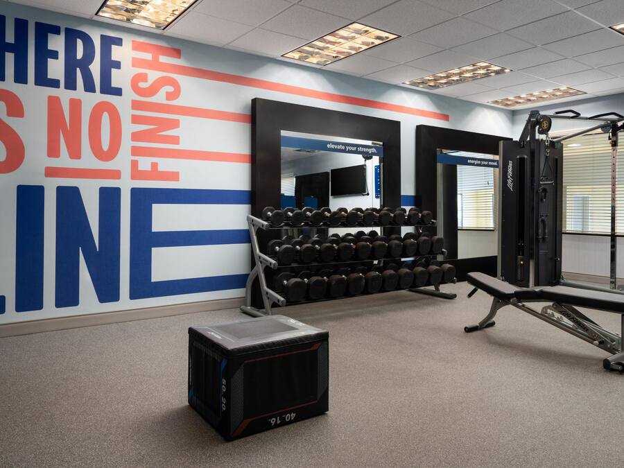 Un gimnàs amb equipament de musculació, una pica i un mur motivacional.