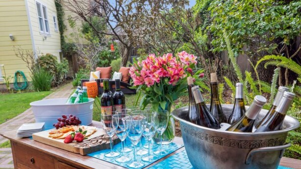 A wooden outdoor bar set with a variety of snacks, wine glasses, and bottles in a bucket. - Parker Guest House San Francisco (San Francisco)