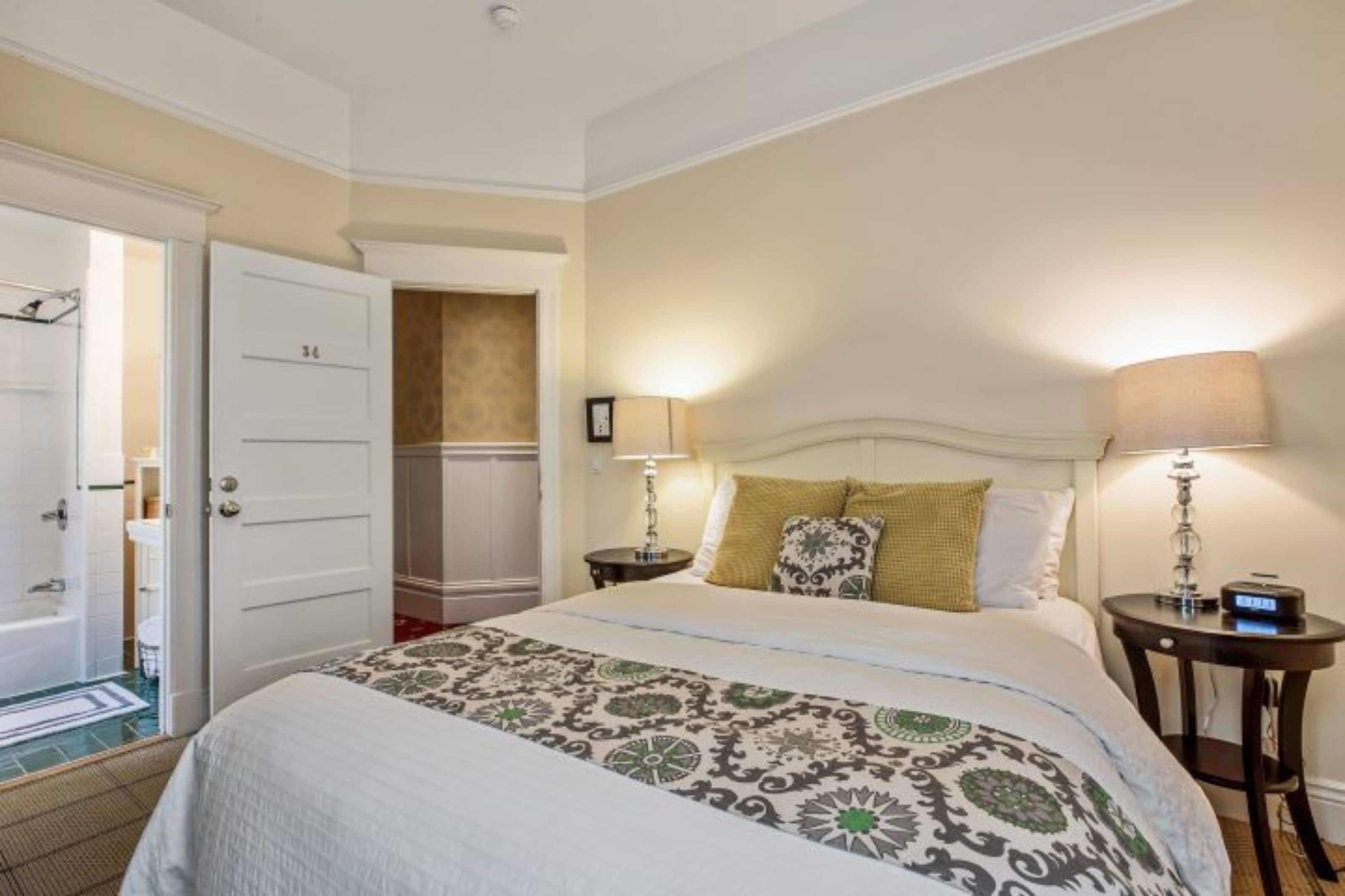 Un dormitorio ordenado con una cama, dos mesitas de noche y un tocador.