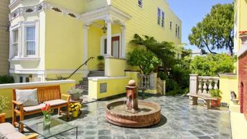 A yellow building with a fountain, outdoor seating, and a staircase leading to the entrance.