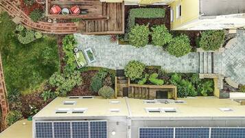 Vue aérienne d’un jardin sur le toit, avec un espace aménagé pour s’asseoir, des panneaux solaires et un petit élément décoratif aquatique.