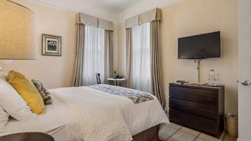 A hotel room with a bed, a dresser, a television, and curtains.