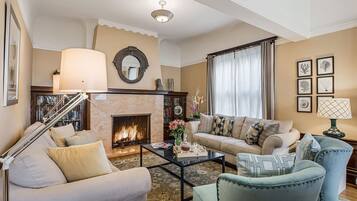 A living room with a fireplace, sofa, armchairs, and a coffee table.