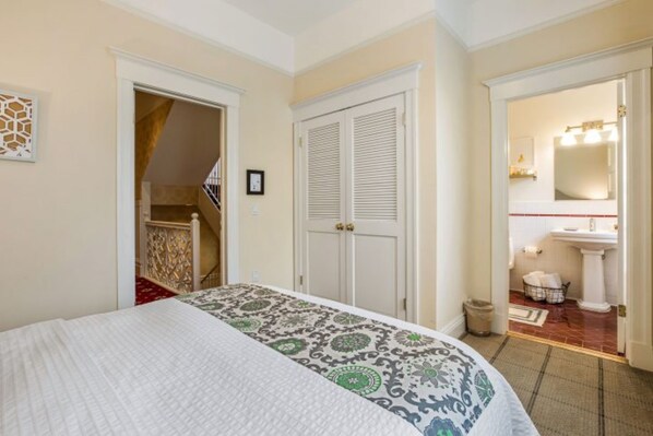 A bedroom with a bed, a closet, and a bathroom visible through an open door.