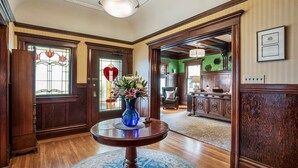 A traditional interior with a wooden floor, a round table with a blue vase, and a stained glass door. - Parker Guest House San Francisco (San Francisco)