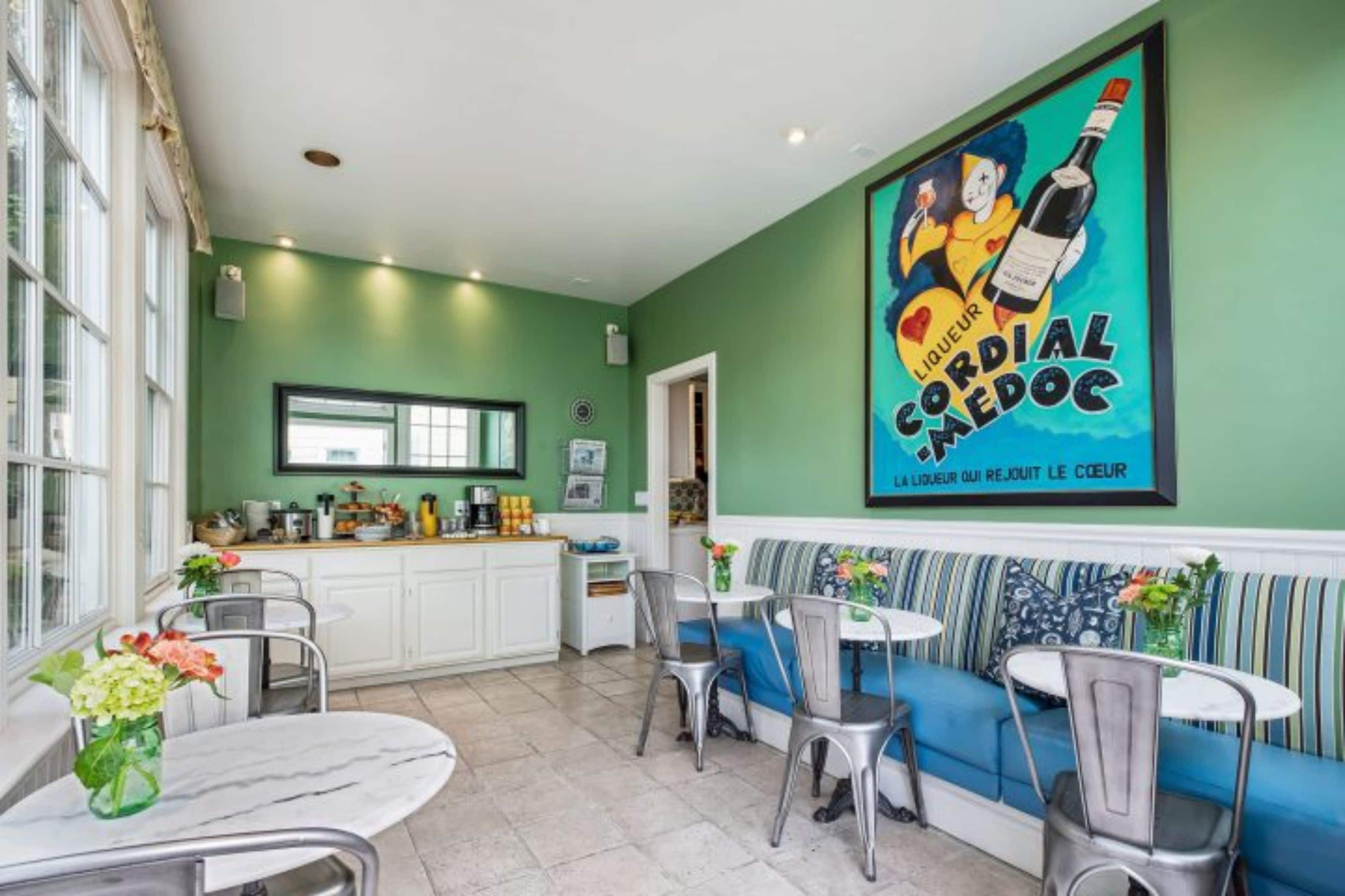 A cozy dining area with a green wall, a large poster, and a sofa with striped cushions.