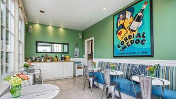 A cozy dining area with a green wall, a large poster, and a sofa with striped cushions.