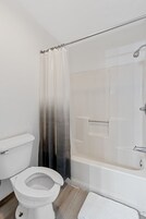Bañera con ducha, toallas, jabón, papel higiénico