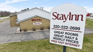Señal de motel StayInn con un número de contacto y destacados de habitaciones excelentes, precios diarios y semanales, e internet rápido gratuito.