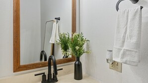 A bathroom with a wooden vanity, a sink, a mirror, a towel rack, and a decorative light fixture.